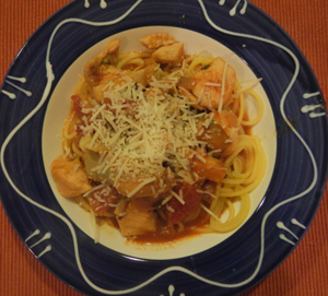 Photo of bowl of Chicken Artichoke & Tomato Saute over past with Parmesan Cheese sprinkled on top