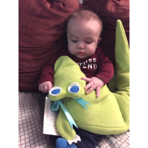 Baby boy with looking at the bright eyes of Al-the-Gator microwave heating pad from Maine Warmers