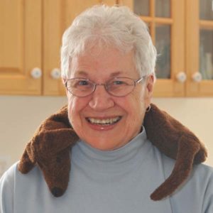 Elderly woman using Dachshund Neck Warmer to relax tense neck muscles