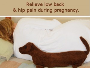 Woman using Dachshund Heating Pad to relieve lower back pain and hip during pregnancy