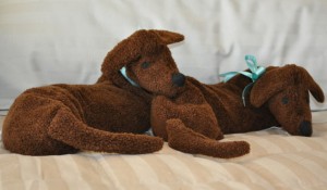 Two Dachshund Neck Warmers on a bed