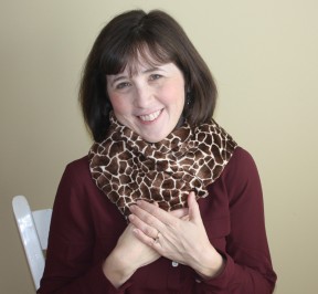Woman using an extra long microwave neck warmer in giraffe print to warm up