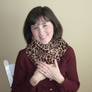 Woman using an extra long microwave neck warmer in giraffe print to warm up