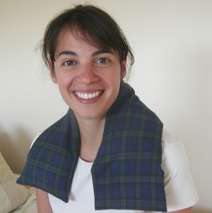 Woman using microwave heating pad for the neck in Black Watch plaid flannel to relax stiff muscles