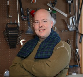 Man using extra long heating pad for his neck in a basement workshop