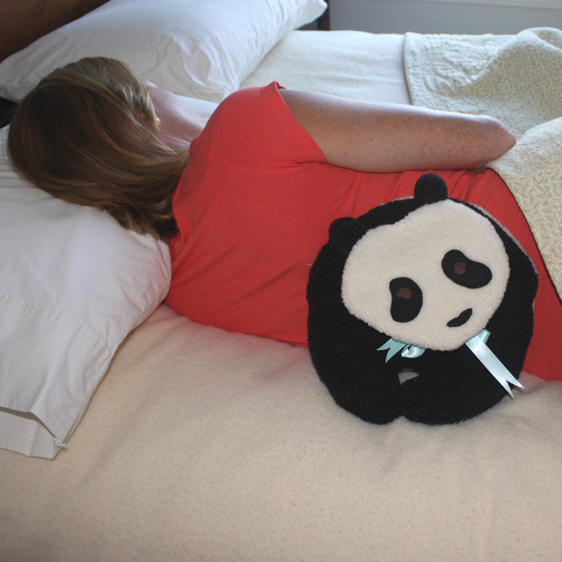 Woman relaxing back muscles with a Panda Bear microwave heating pad