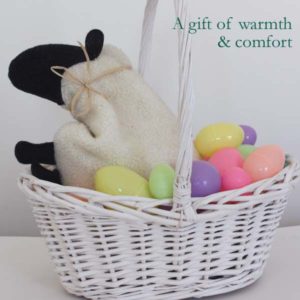 White sheep with black face in Easter basket with colored eggs