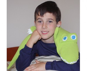 Boy using alligator microwave heating pad as a bed warmer