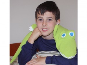 Boy using alligator microwave heating pad as a bed warmer