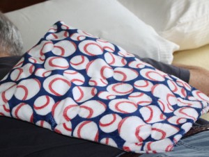 Man relaxing stiff back muscles with a Maine Warmers' microwave back warmer in a soft, baseball print.
