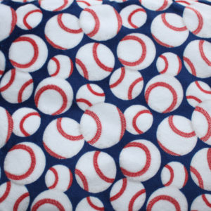 Print plush fabric with blue background, white baseballs and red stitching for baseball enthusiasts