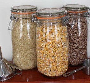 Three glass jars each filled with whole corn, whie rice, and dried Pinto beans for filling microwave heating pads