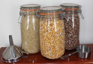 Three glass jars each filled with whole corn, whie rice, and dried Pinto beans for filling microwave heating pads