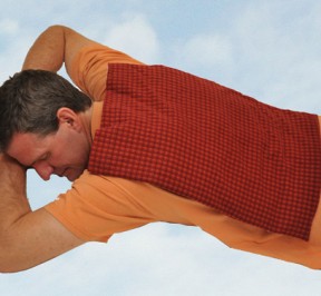 Man using extra large microwave heating pad to relax stiff back muscles, feeling great, and floating on some clouds