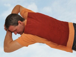 Man using extra large microwave heating pad to relax stiff back muscles, feeling great, and floating on some clouds