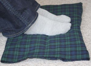 Feet resting on a reusable, washable foot warmer pad that can also be used as an extra large Back Warmer.