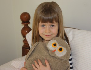 Girl warming hands on tan owl microwave bed warmer