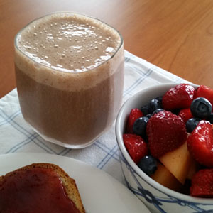 Chocolate Banana Smoothie with a bowl of fruit and toast with strawberry jam