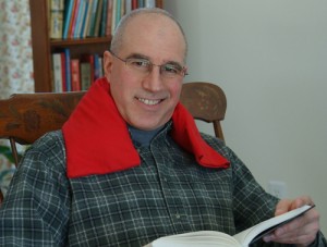 Man relieving sore neck muscles with a red microwave neck warmer