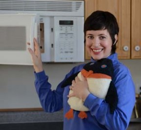 Woman warming hands on a Penguin microwave heating pad that just came out of the microwave oven