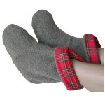 Someone resting their feet with a pair of gray foot warmers with Scotch red plaid lining that are microwaveable