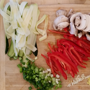 Zucchini noodles and other cut veggies on a cutting board