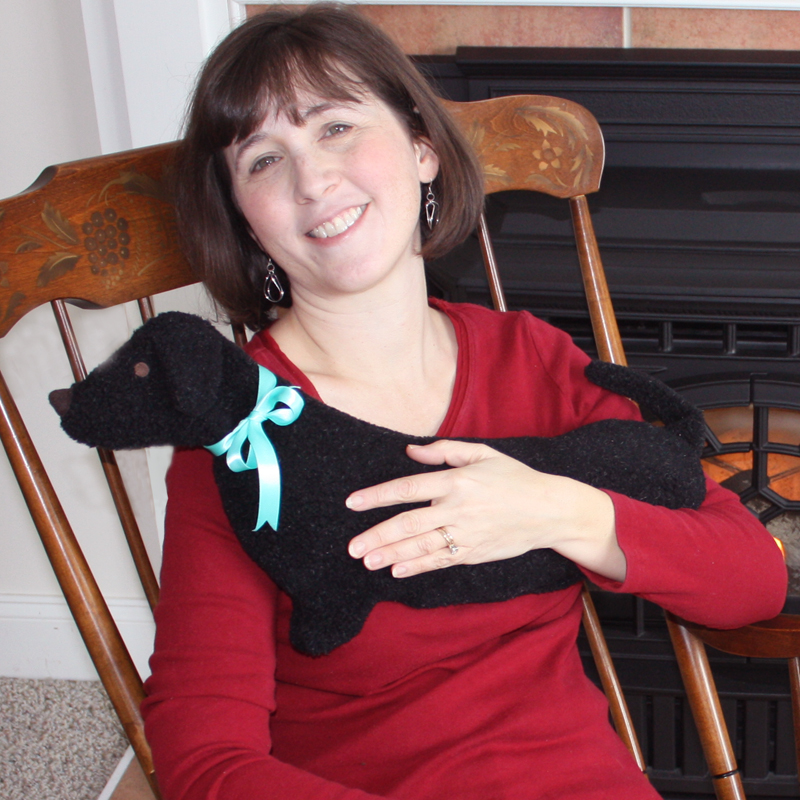 Woman relaxng with black dachshund microwaveable neck wrap